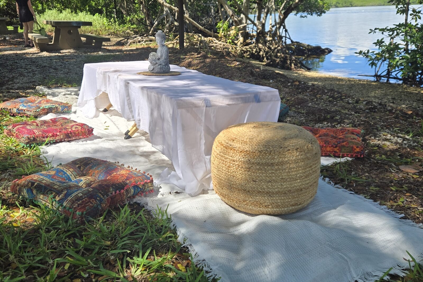 The setup beside the water, with a row of cushions along a white runner.