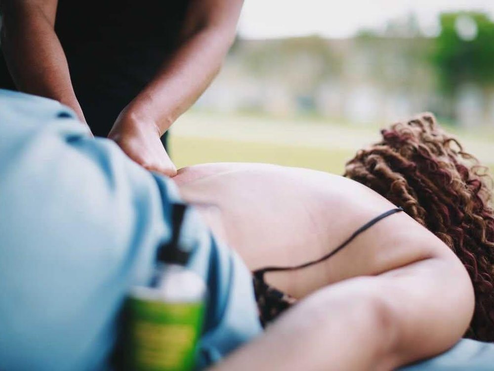 A therapist's hands working on a client's back outdoors
